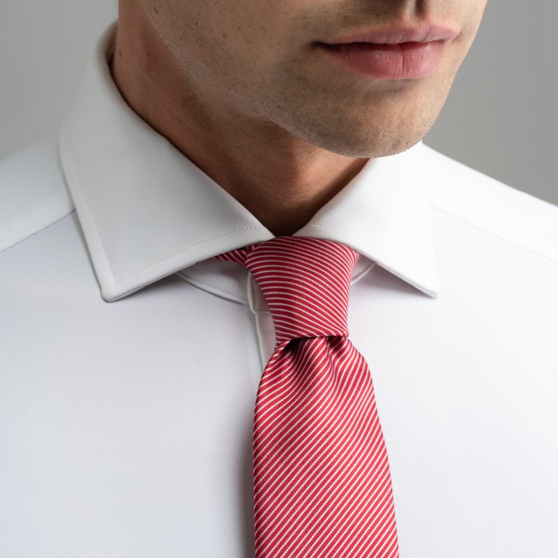 Dettaglio colletto camicia bianca con cravatta rossa a righe